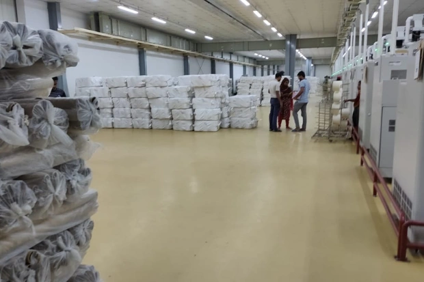 Beige epoxy floor in a garment factory store with stacked fabric bales