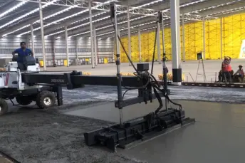 Laser screed machine levelling a super flat concrete warehouse slab