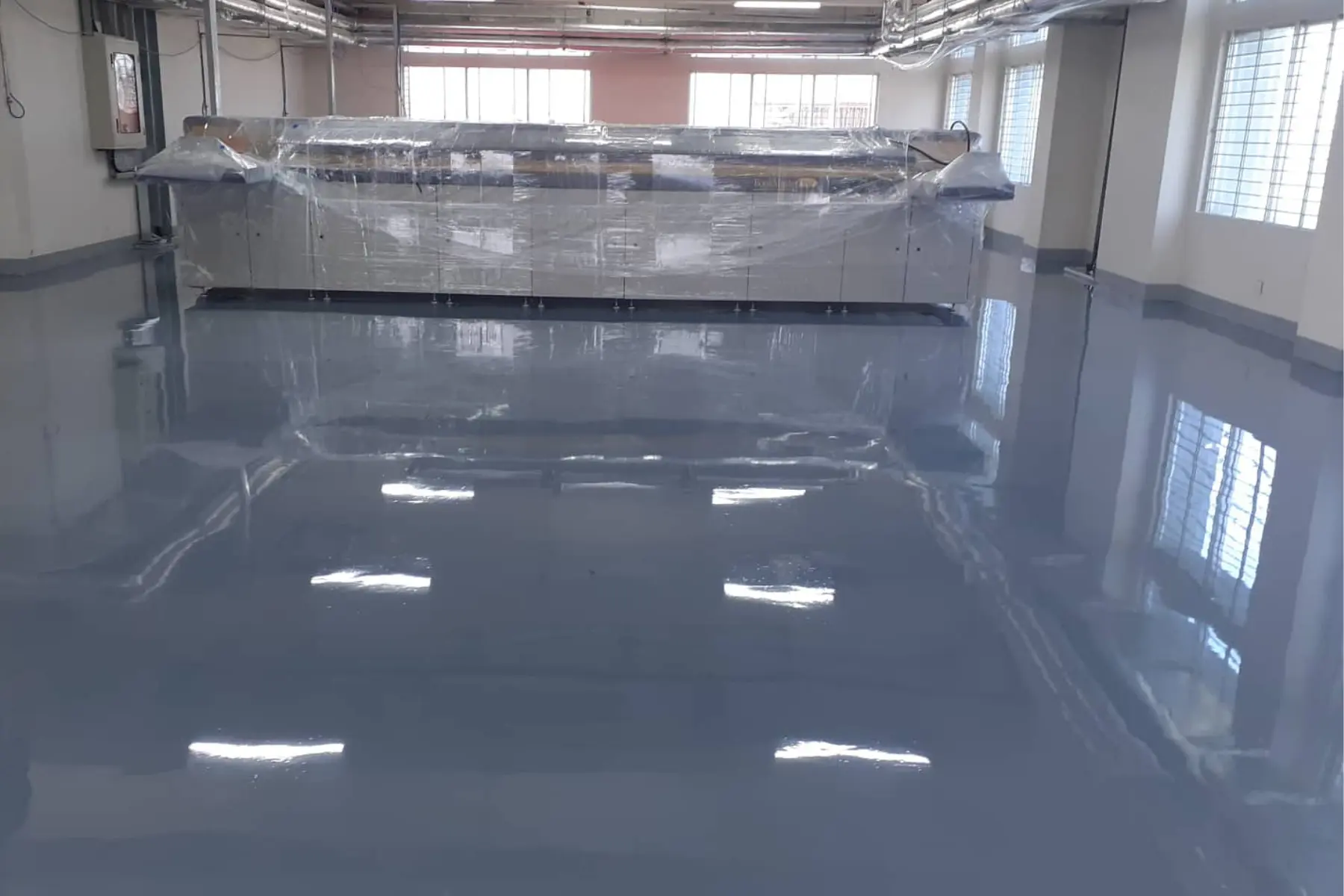 High-gloss grey epoxy floor reflecting ceiling lights