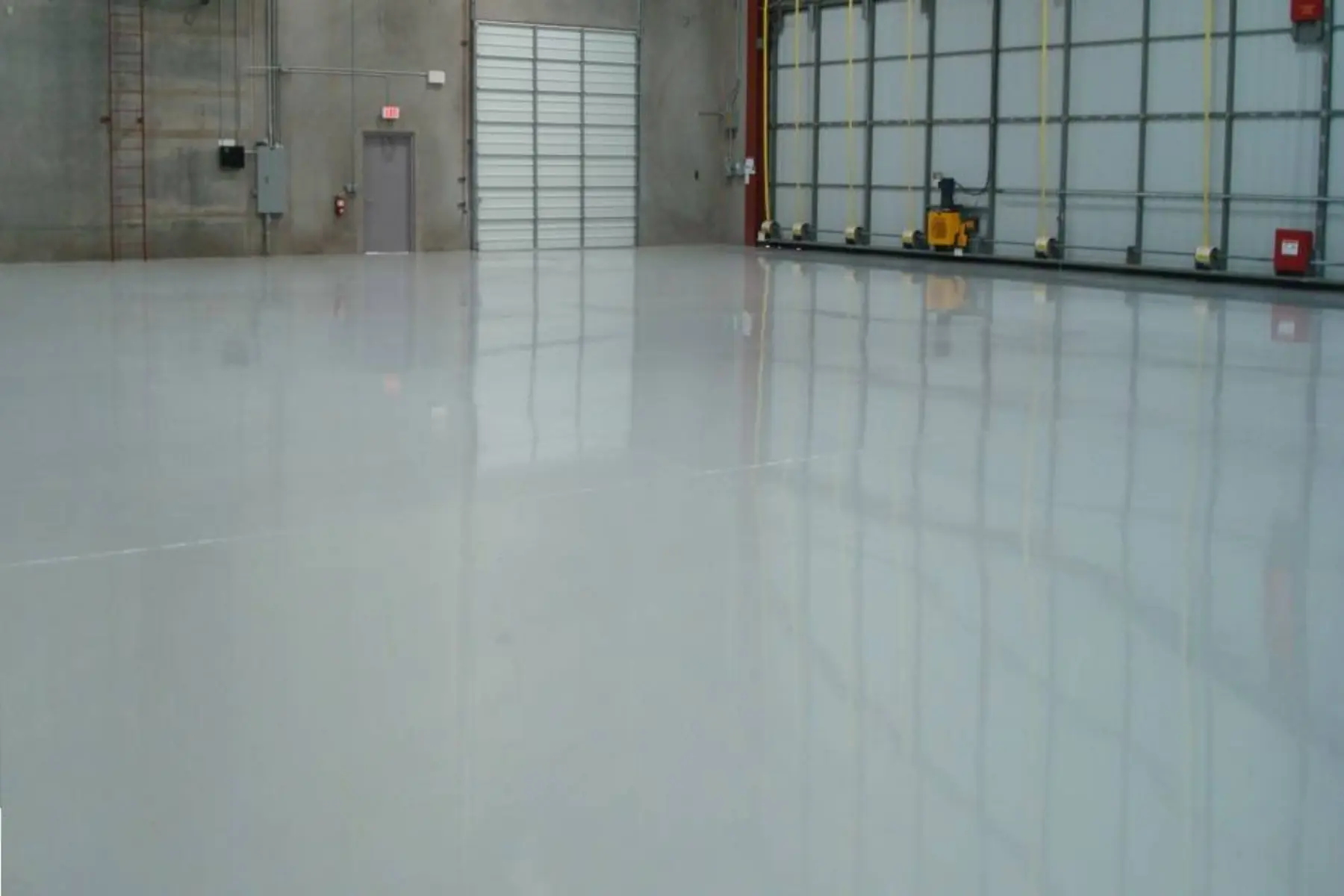 Glossy light grey epoxy floor in an empty factory hall