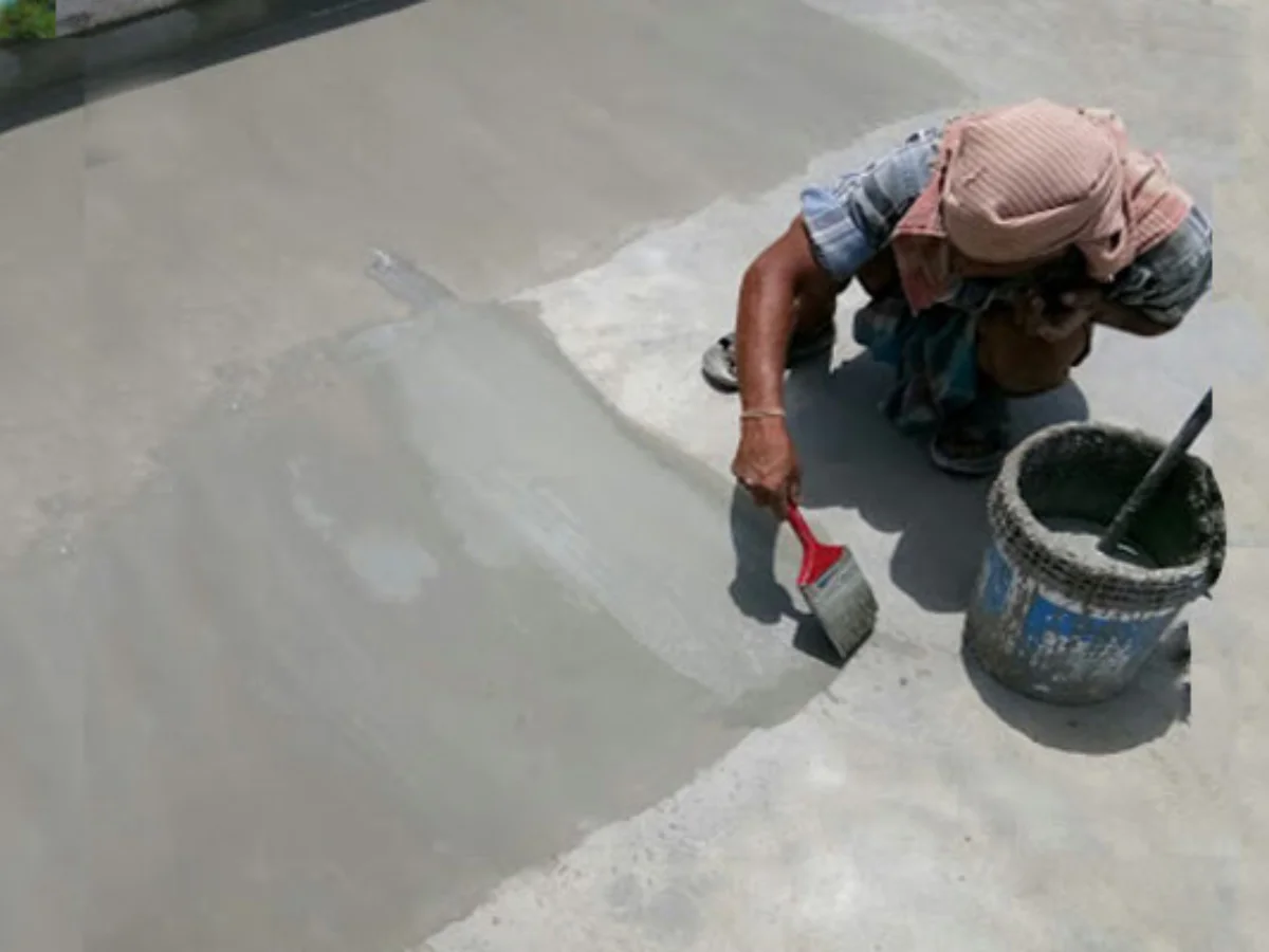 Applying cementitious waterproofing coat with brush and bucket