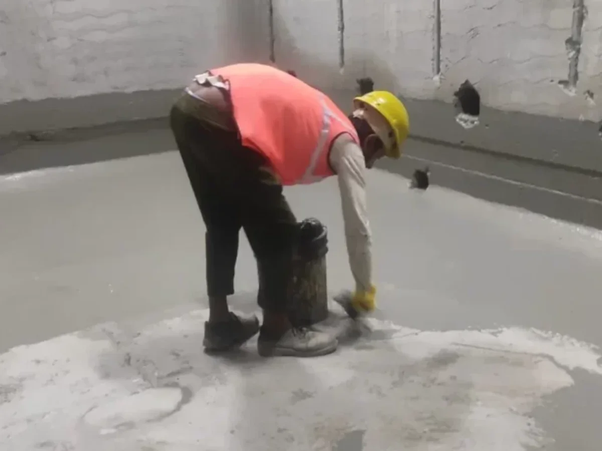 Worker preparing cementitious waterproofing mix on site